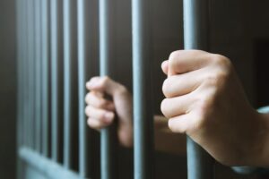 person in jail holding the bars